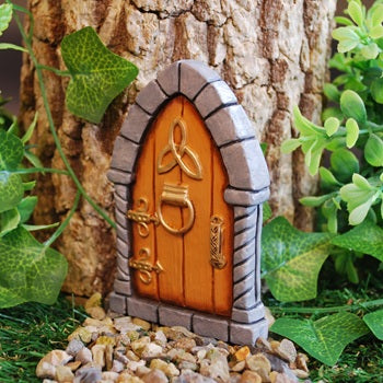 Miniature fairy door with Celtic knot design on a tree trunk