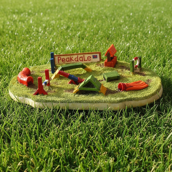 Dog Agility scene on a grassy base, featuring a sign that reads 'Peakdale' and small colorful structures and equipment.