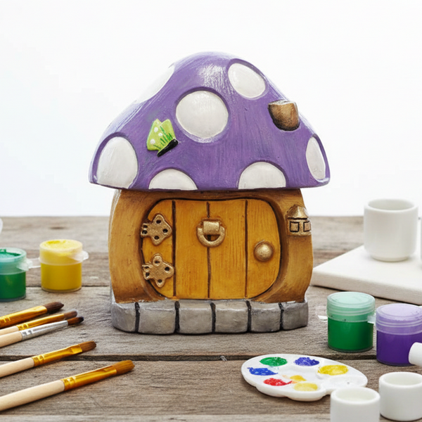 A small mushroom-shaped decorative house figurine with a lilac cap, white  dots, a light brown wooden door, and a grey stone base