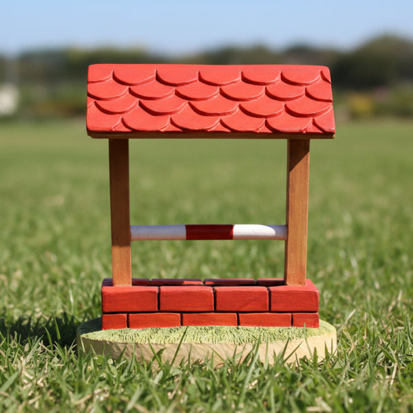 A figurine of a dog agility trophy with a red brick wall and a red roof 